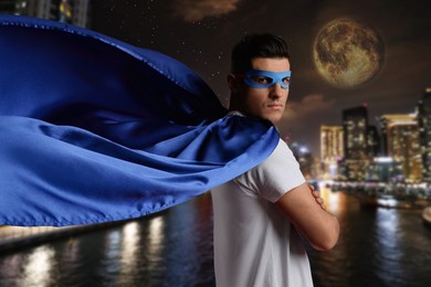 Image of Man wearing wearing superhero costume and beautiful cityscape in night on background