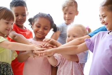 Photo of Little children putting their hands together on light background. Unity concept