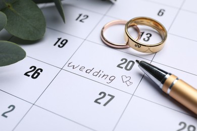 Calendar with date reminder about Wedding Day, pen and rings, closeup