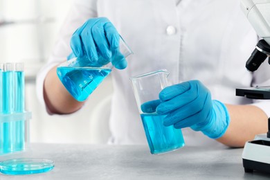 Photo of Scientist working with beakers in laboratory, closeup