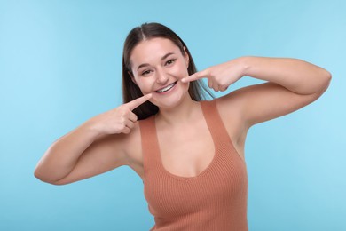 Happy woman showing braces on her teeth against light blue background