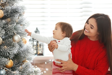 Mother and her cute baby near Christmas tree at home