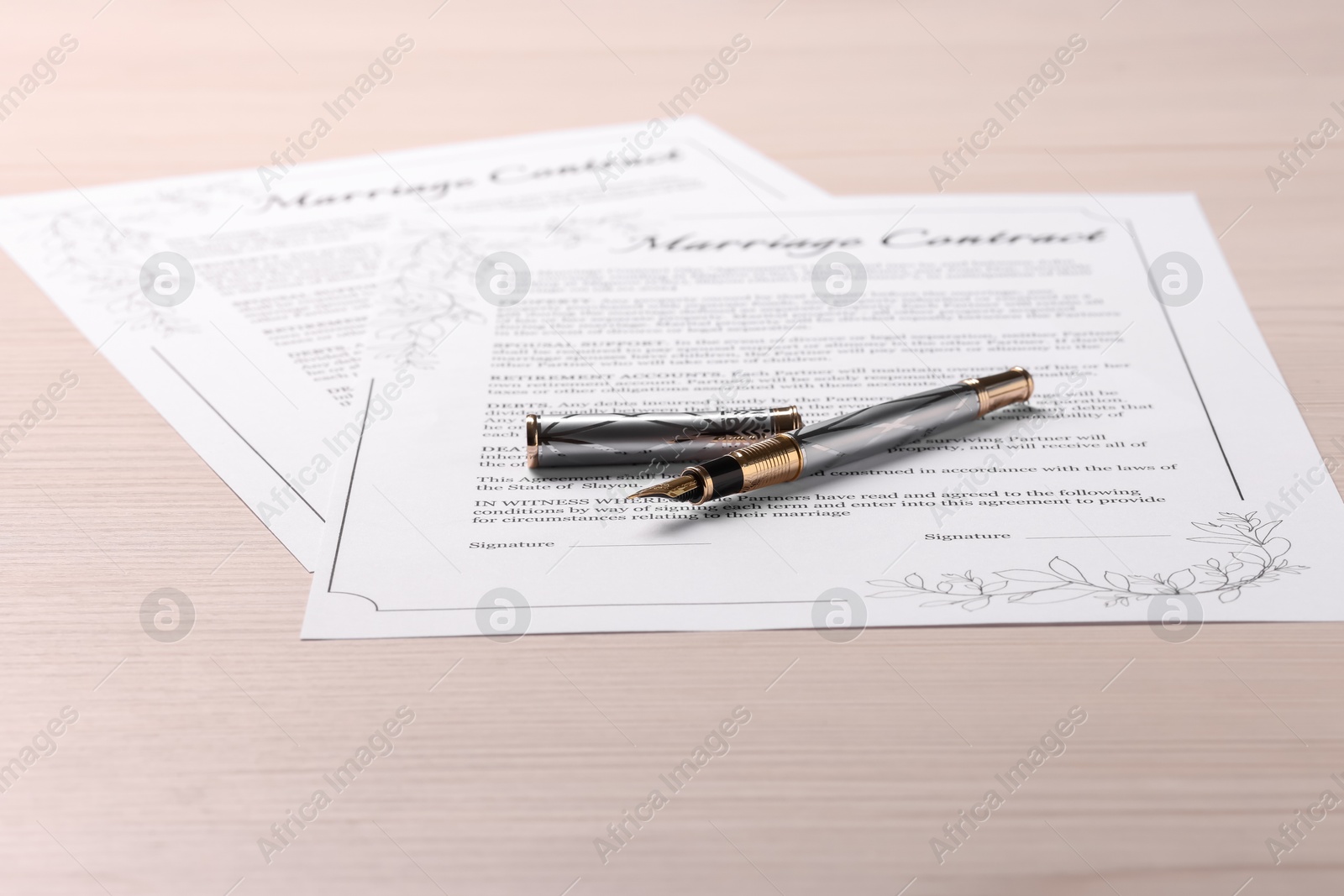 Photo of Marriage contracts and pen on light wooden table