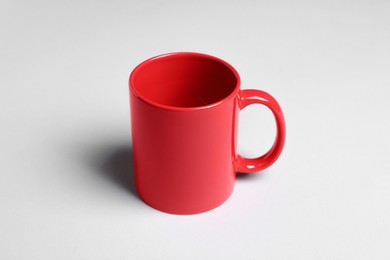 Photo of One red ceramic mug on light background