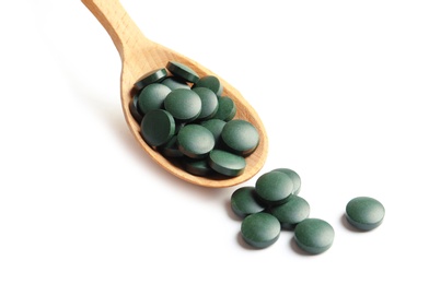 Photo of Spoon with spirulina tablets on white background