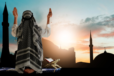Image of Muslim man praying and silhouette of mosque on background