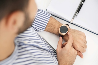 Photo of Man checking smart watch at desk in office, closeup