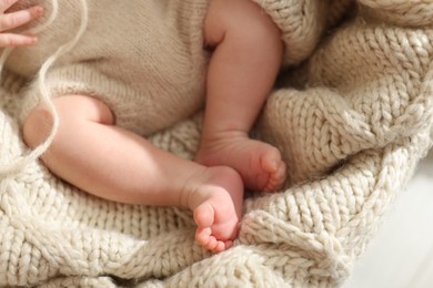 Photo of Adorable newborn baby on knitted plaid, closeup