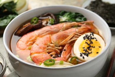 Delicious ramen with shrimps and egg in bowl on table, closeup. Noodle soup