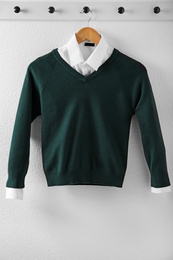 Photo of Shirt and jumper on hanger indoors. School uniform