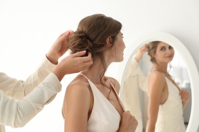 Photo of Hair stylist preparing bride for her wedding indoors