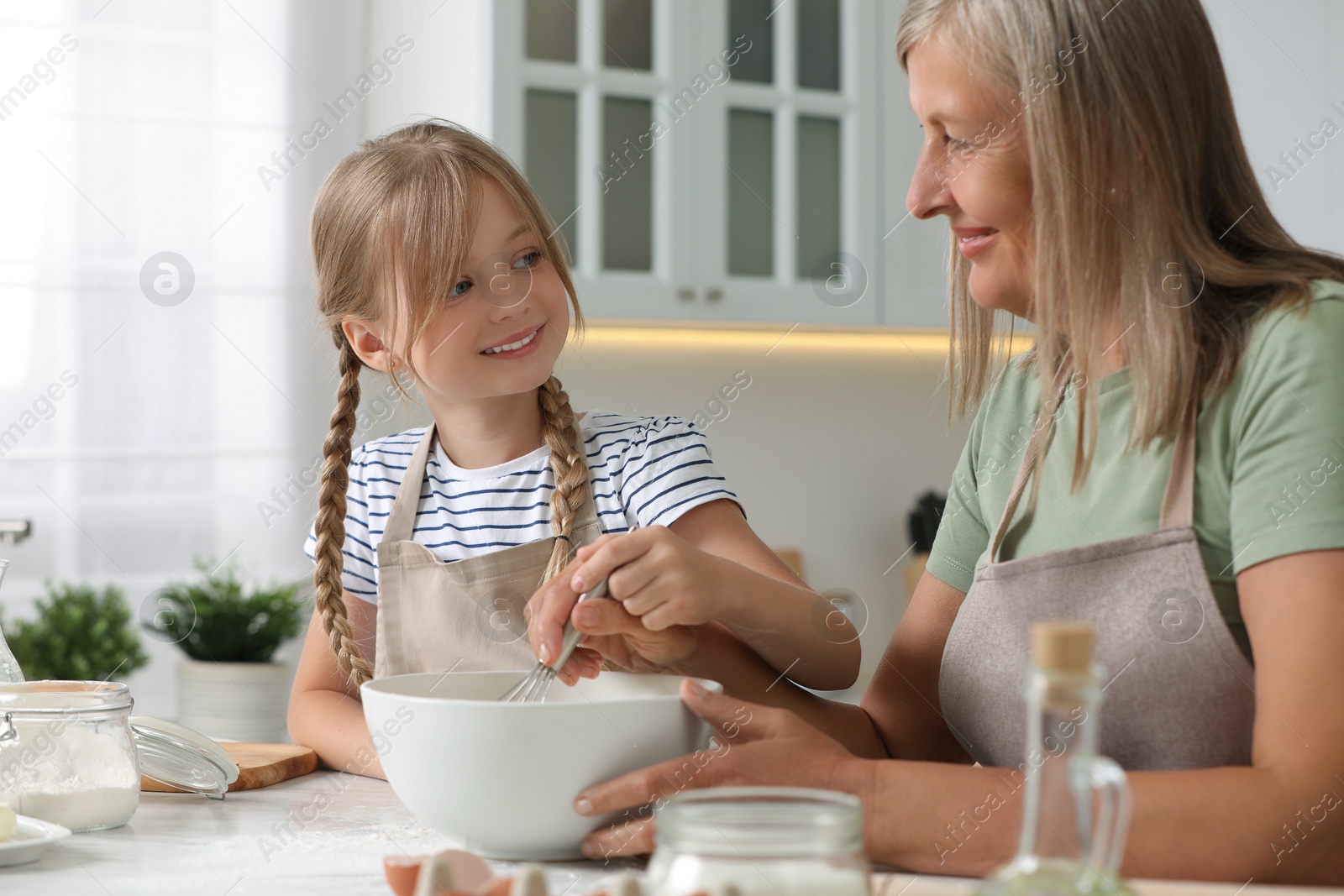 Photo of Happy grandmother with her granddaughter cooking together in kitchen