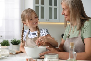 Happy grandmother with her granddaughter cooking together in kitchen