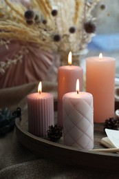 Tray with burning wax candles on window sill indoors