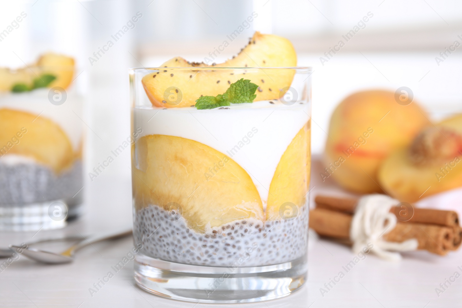 Photo of Tasty peach dessert with yogurt and chia seeds on white wooden table