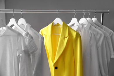 Yellow jacket hanging on rack among other clothes. Diversity concept