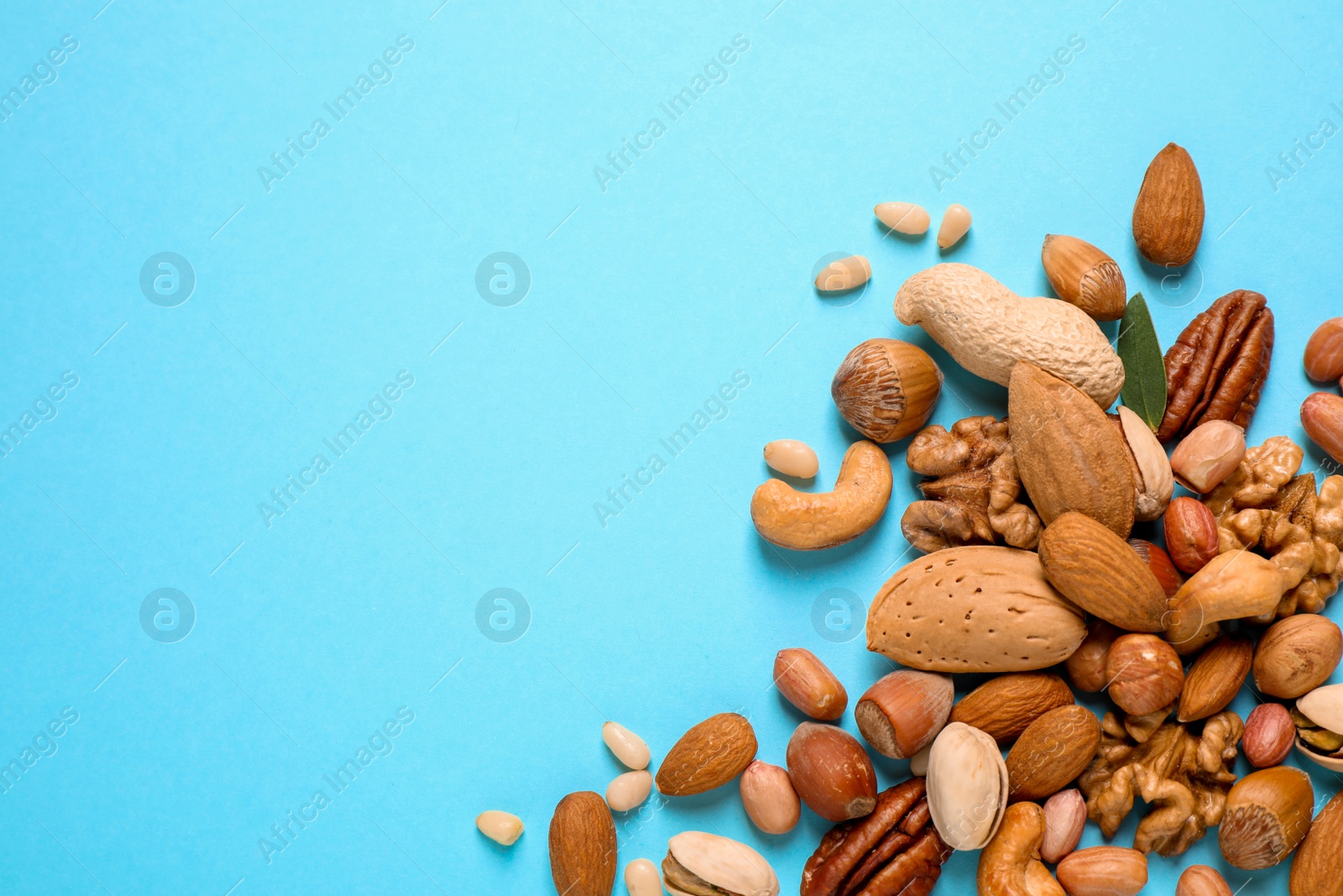 Photo of Different delicious nuts on light blue background, flat lay. Space for text