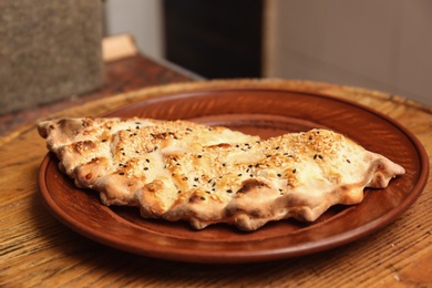 Photo of Plate with calzone on wooden table in restaurant. Fresh from oven