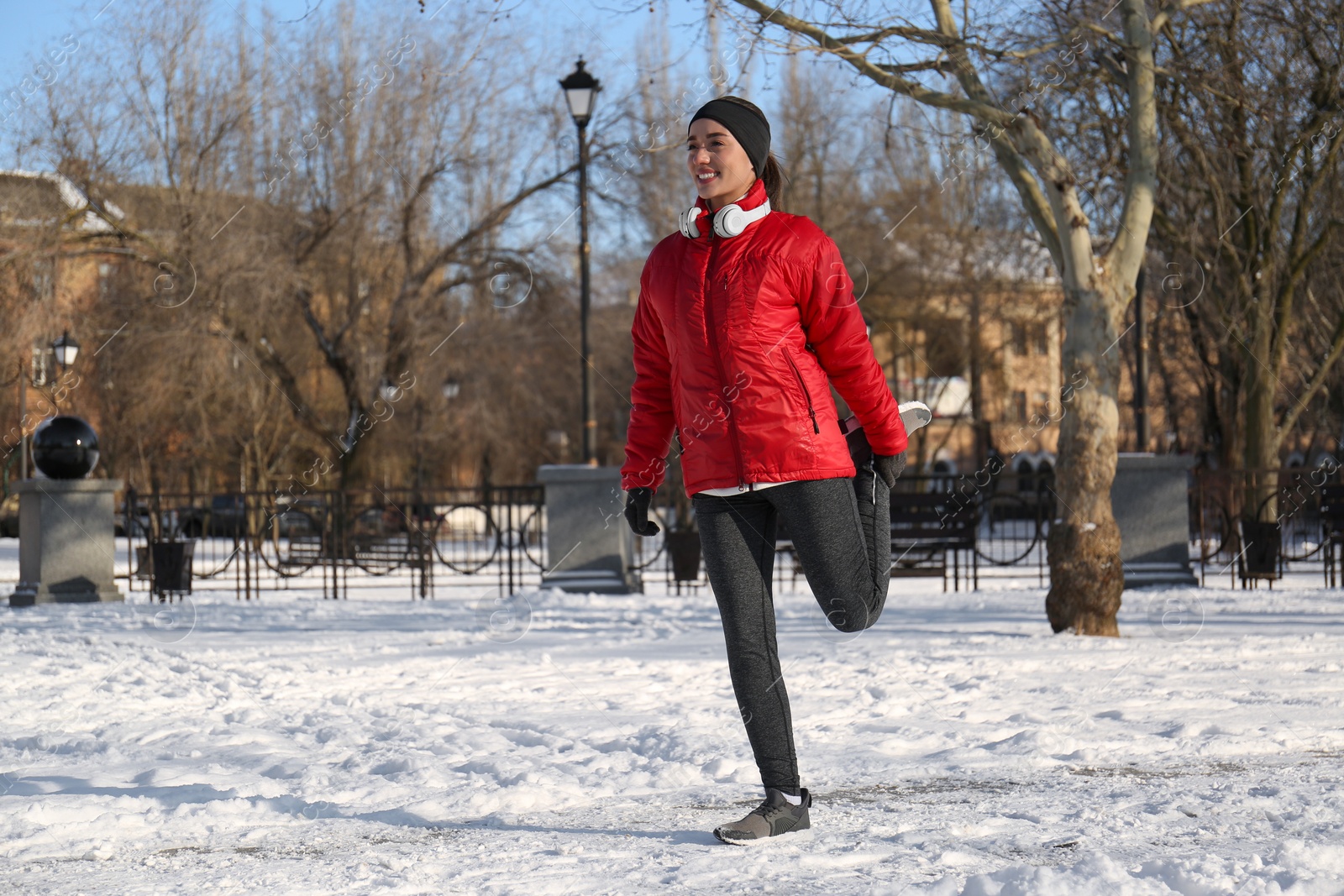 Photo of Happy woman doing sports exercises in snowy park on winter day