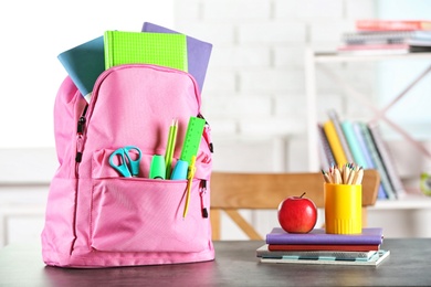 Photo of Backpack with school stationery on table indoors