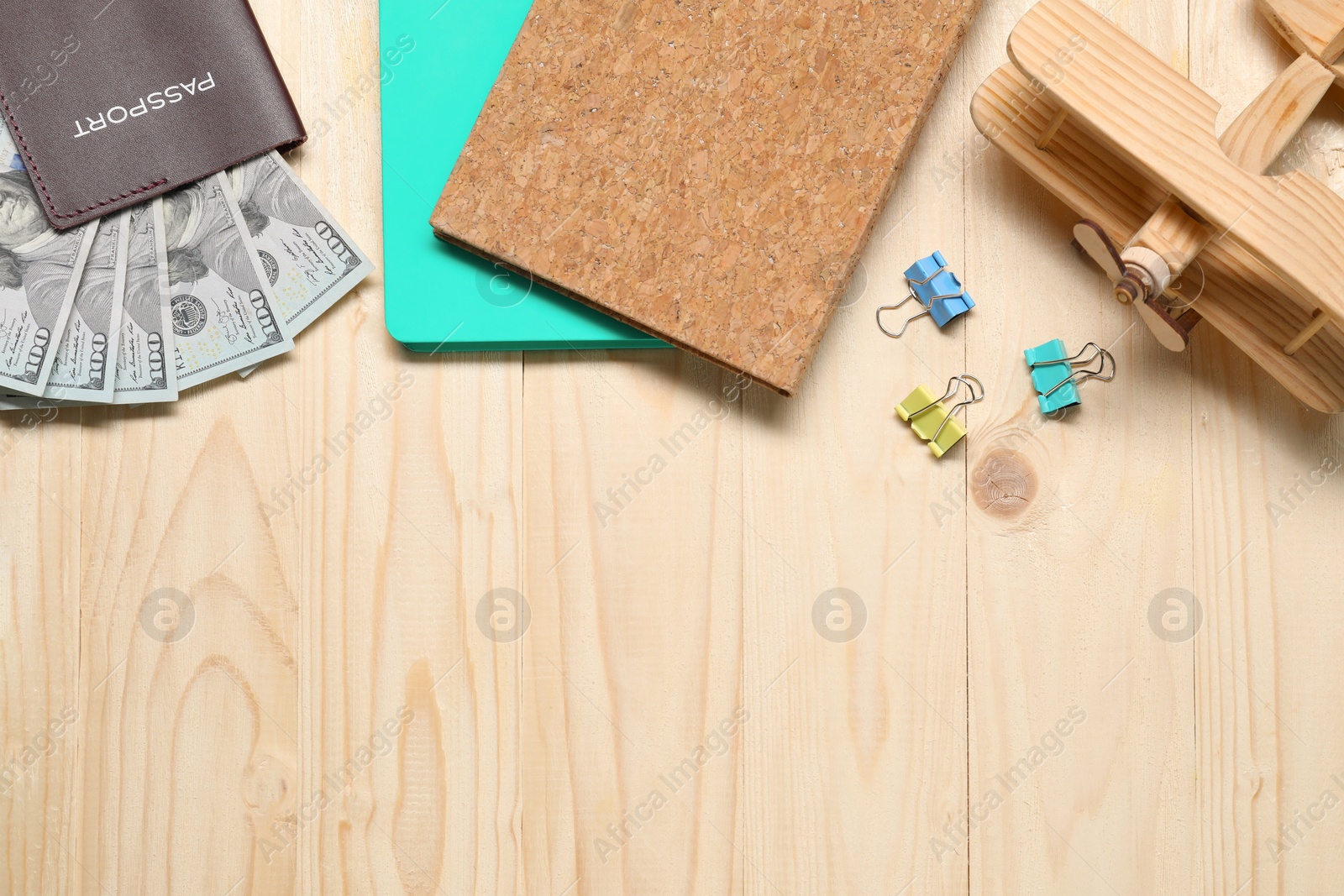 Photo of Flat lay composition with dollars, model of plane and passport on wooden table, space for text. Business trip