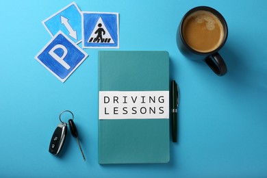 Flat lay composition with workbook for driving lessons on light blue background. Passing license exam