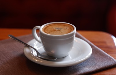 Cup of hot aromatic coffee served on wooden table in cafe. Space for text