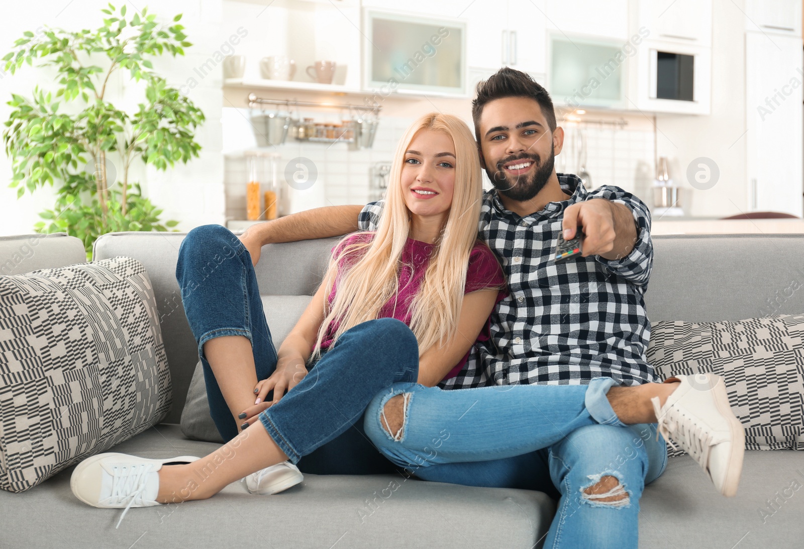 Photo of Young couple watching TV on sofa at home