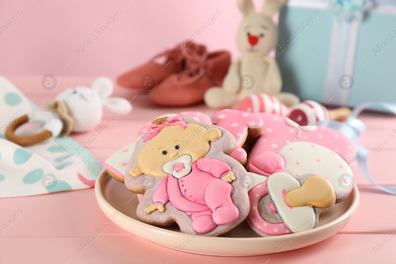 Photo of Tasty cookies of different shapes on pink wooden table. Baby shower party