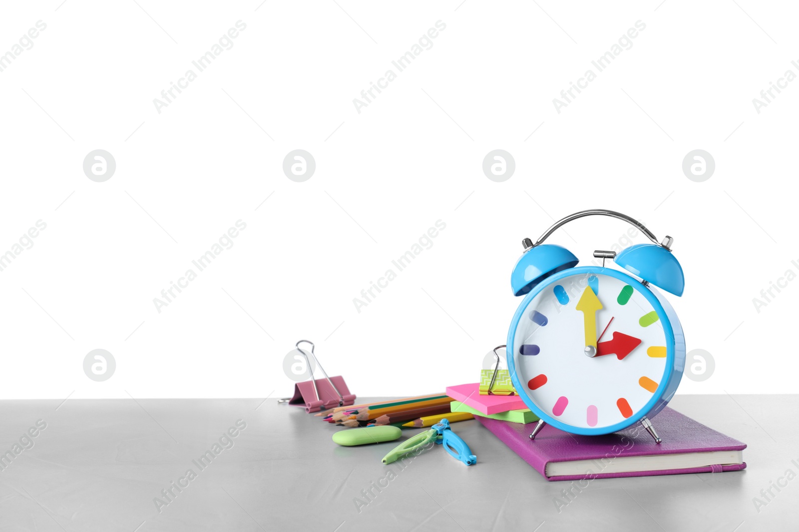 Photo of Light blue alarm clock and different stationery on wooden table against white background, space for text. School time