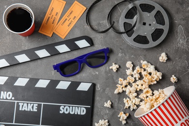 Photo of Flat lay composition with clapper and popcorn on grey background. Cinema snack