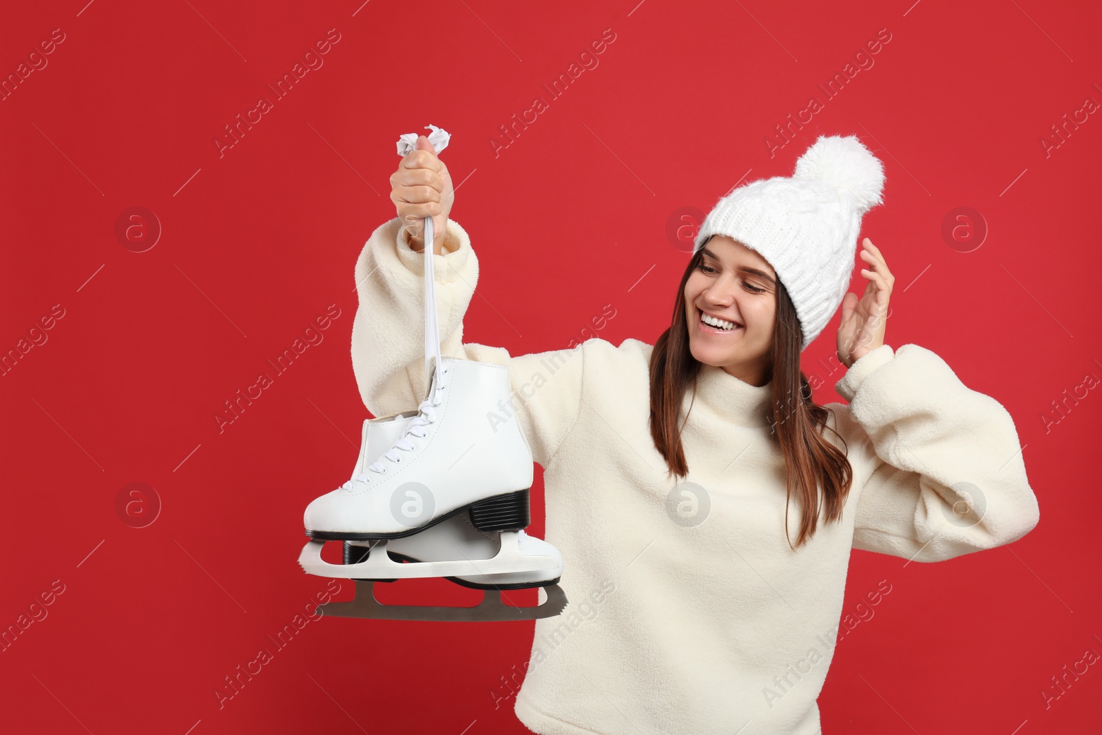 Photo of Happy woman with ice skates on red background