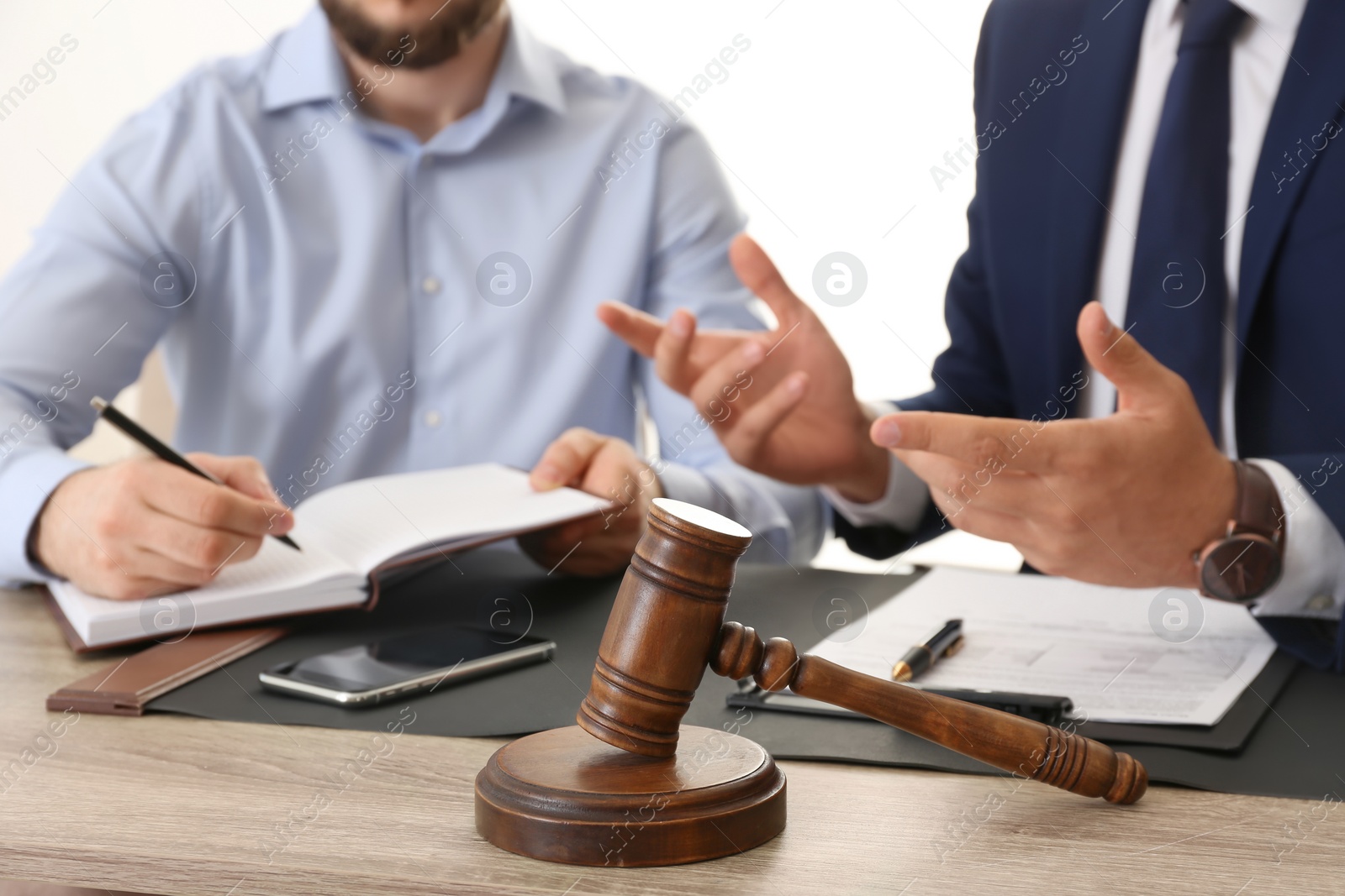 Photo of Gavel and blurred lawyer working with client on background