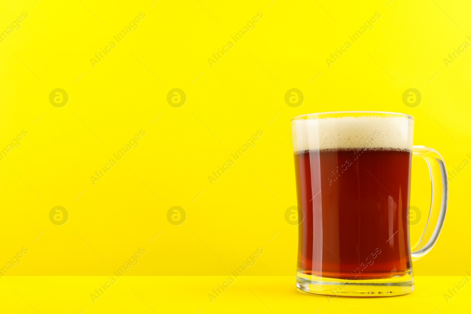 Photo of Delicious homemade kvass in glass mug on yellow background. Space for text