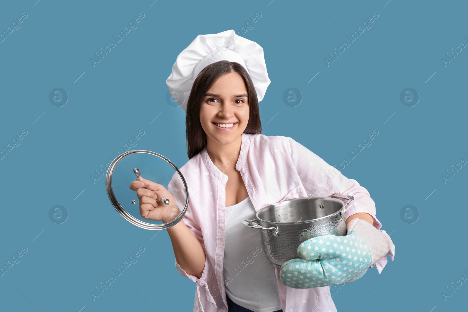 Photo of Happy young woman with cooking pot on light blue background