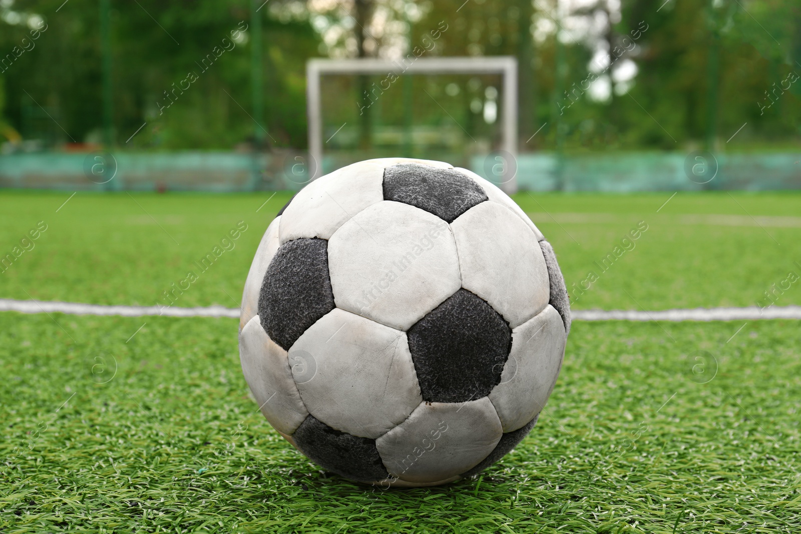 Photo of Dirty soccer ball on green football field, closeup