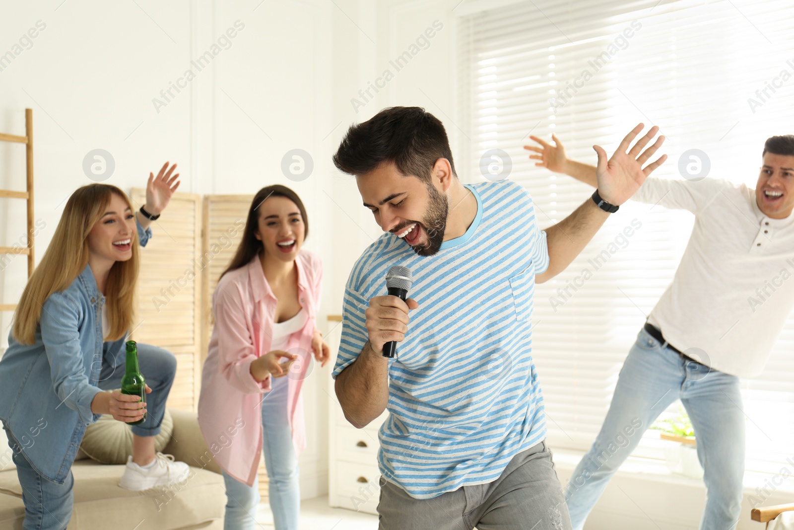 Photo of Young man singing karaoke with friends at home