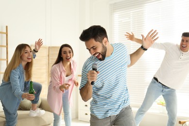 Young man singing karaoke with friends at home