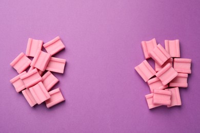 Photo of Tasty pink chewing gums on purple background, flat lay. Space for text