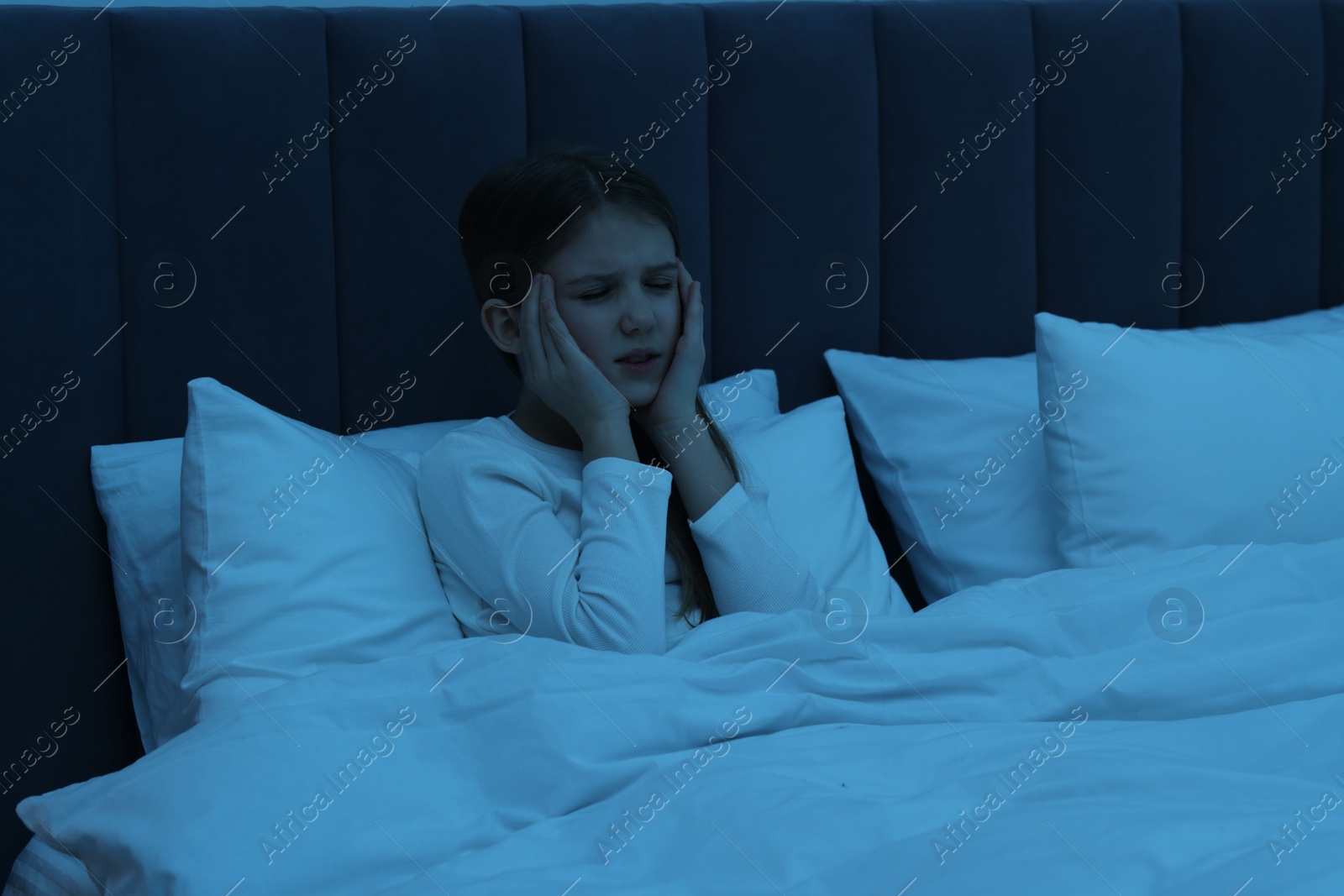 Photo of Little girl suffering from headache in bed at night