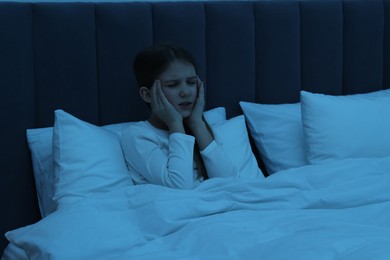 Photo of Little girl suffering from headache in bed at night