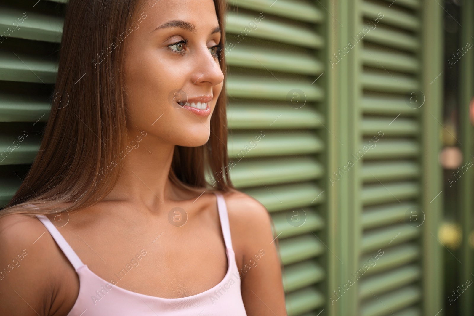 Photo of Beautiful young woman in stylish outfit near shutters, space for text