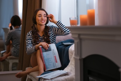 Young woman with newspaper near window at home. Winter atmosphere