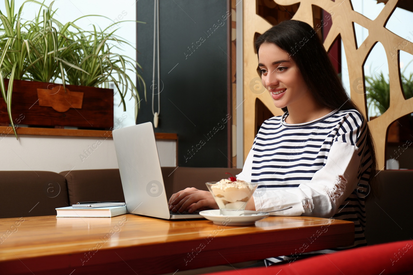 Photo of Young blogger working with laptop in cafe