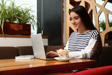 Young blogger working with laptop in cafe