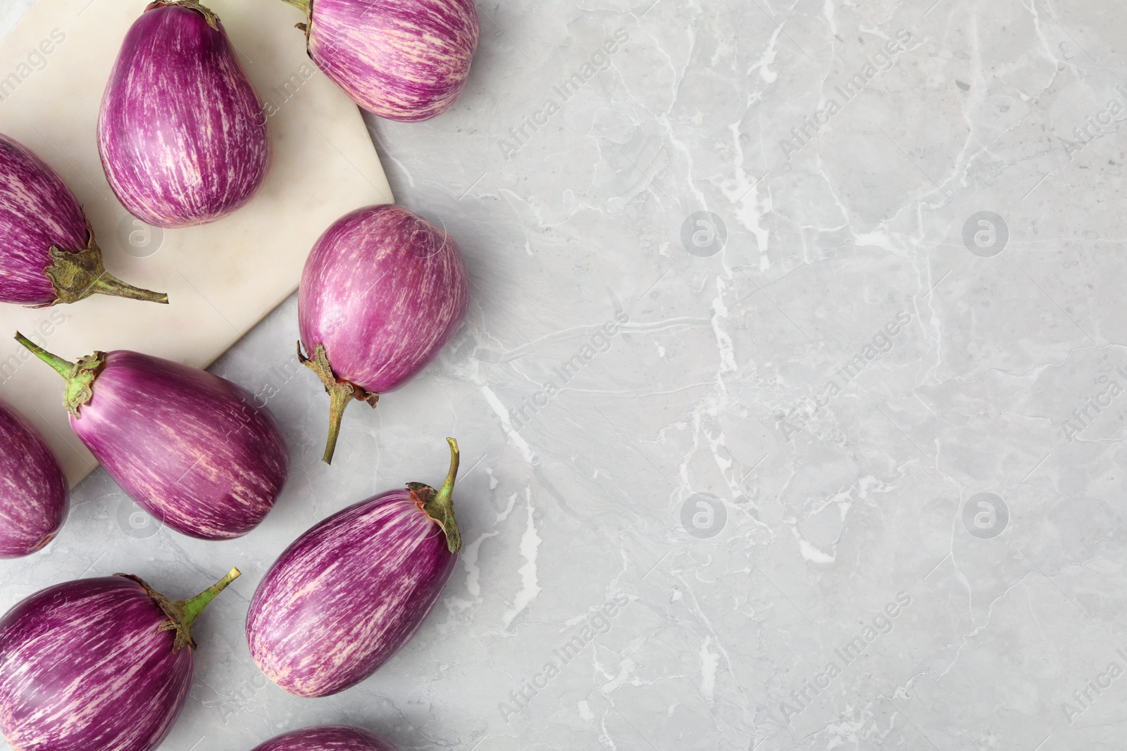 Photo of Raw ripe eggplants on grey table, flat lay. Space for text