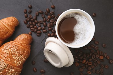 Photo of Coffee to go. Paper cup with tasty drink, croissants and beans on black table, flat lay