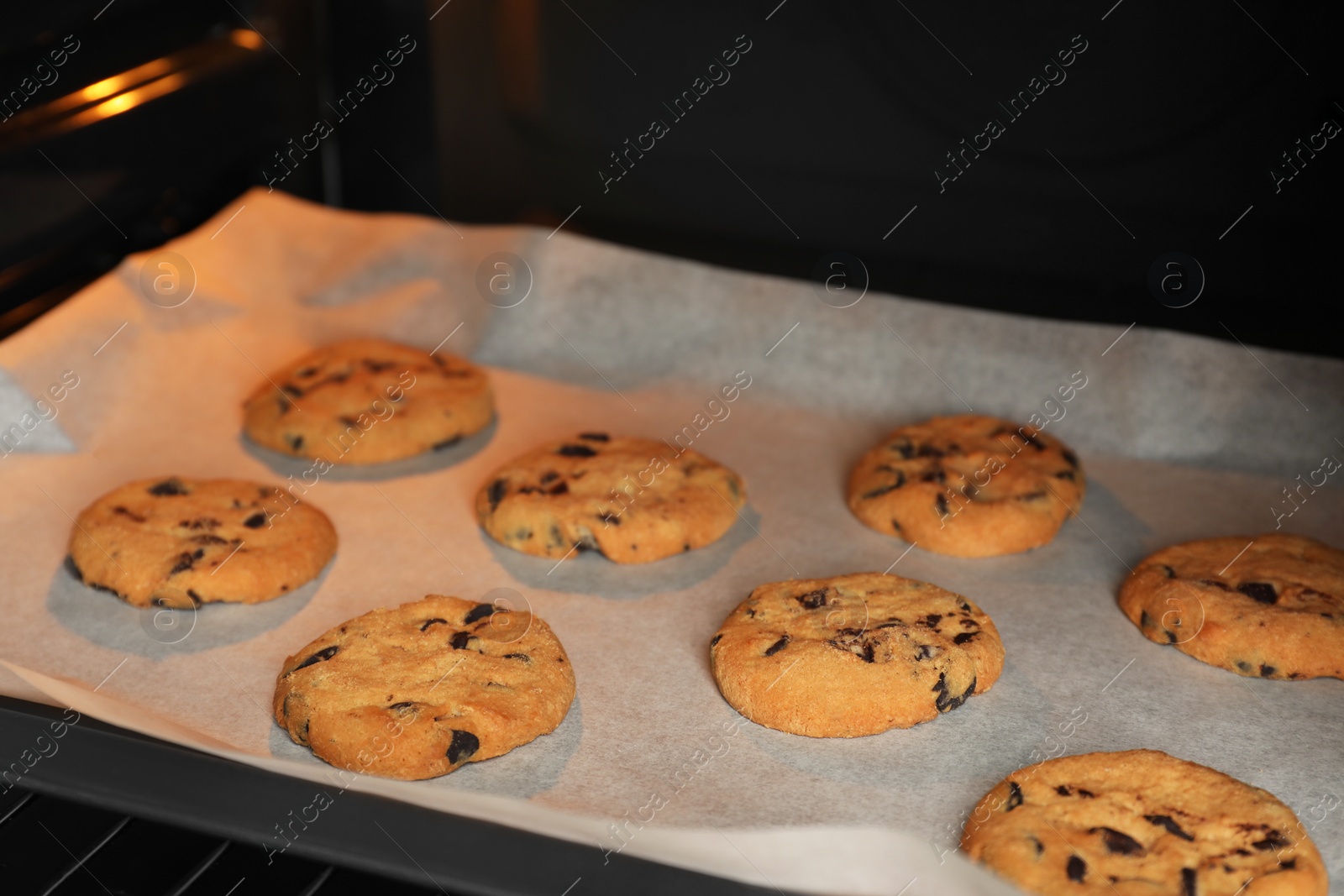 Photo of Baking delicious chocolate chip cookies in oven, closeup