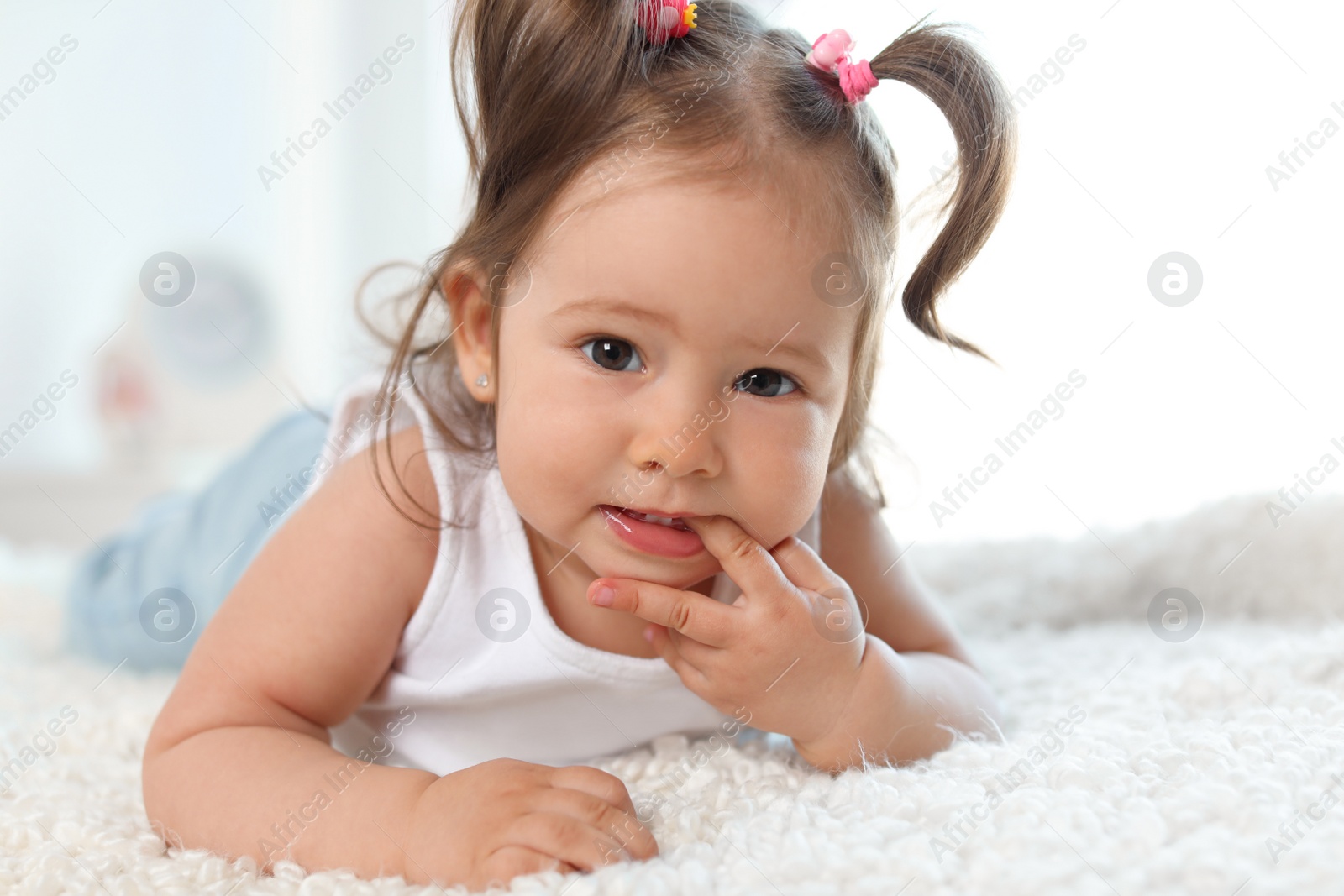 Photo of Adorable little baby girl lying on bed in room