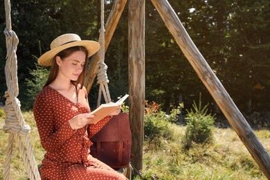 Photo of Beautiful young woman reading book outdoors on sunny day, space for text